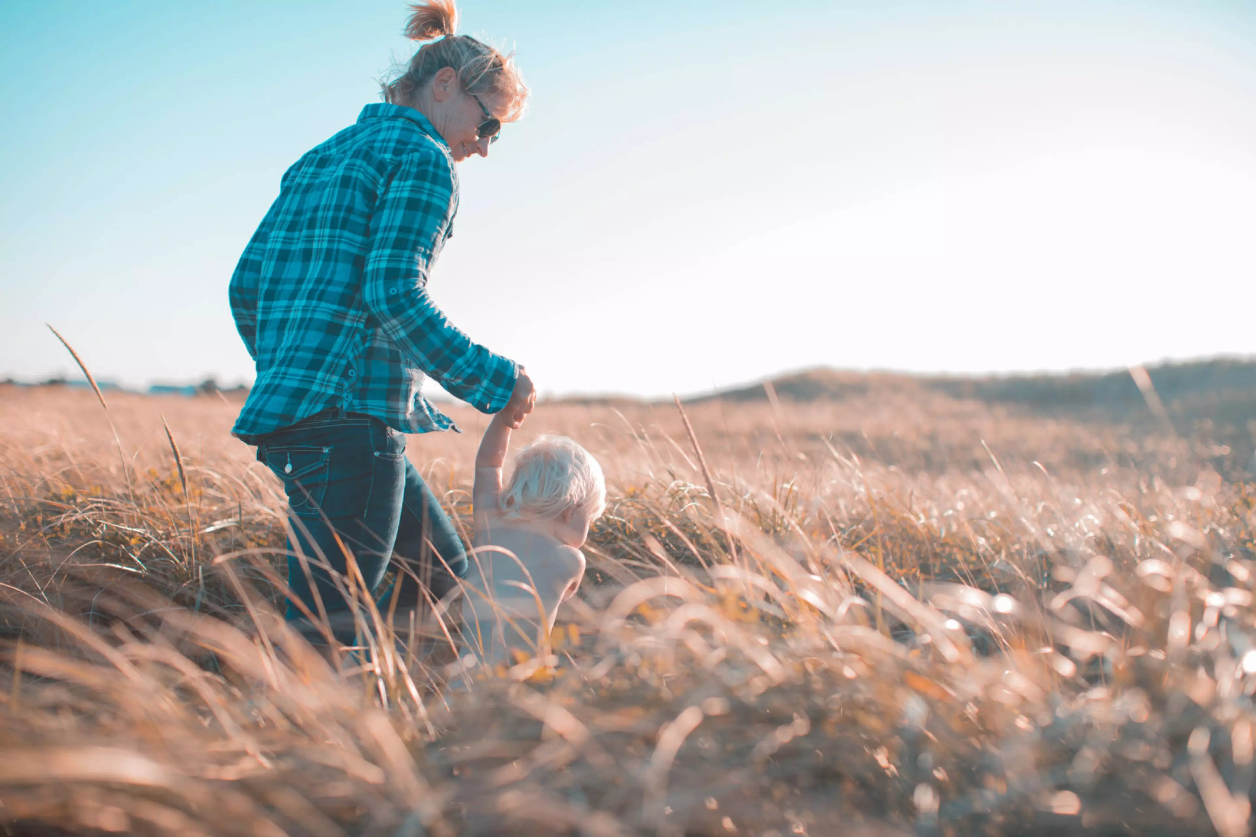 Une femme et son enfant qui courent dans un champs de blé